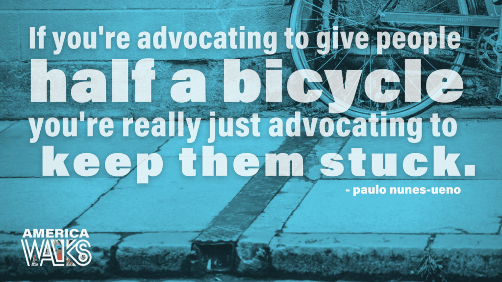 Aqua overlay on top of an image of a bicycle. The quote says "If you're advocating to give people half a bicycle, you're really just advocating to keep them stuck." The quote is attributed to Paulo Nunes-Ueno and there is an America Walks logo