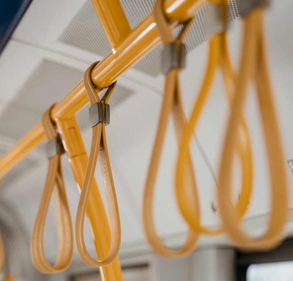 Image of yellow handles hanging on the inside of a bus. 