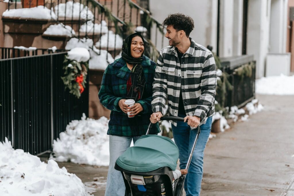 Two people that are walking and looking at each other pushing a stroller