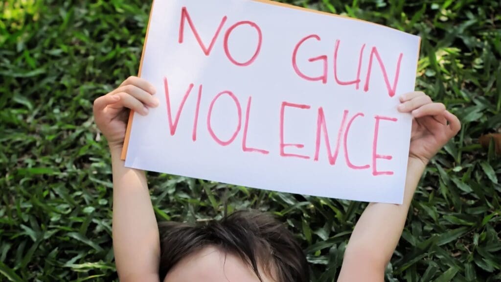 Child holding a sign that says "NO GUN VIOLENCE"