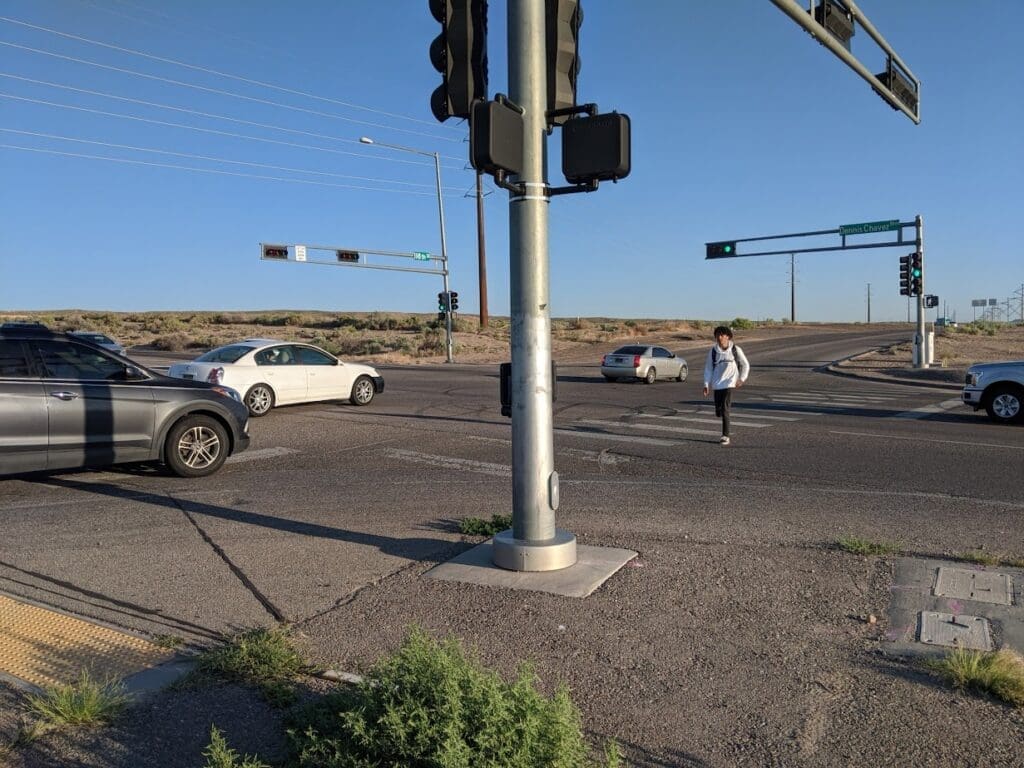 Person crossing a busy intersection with cars.