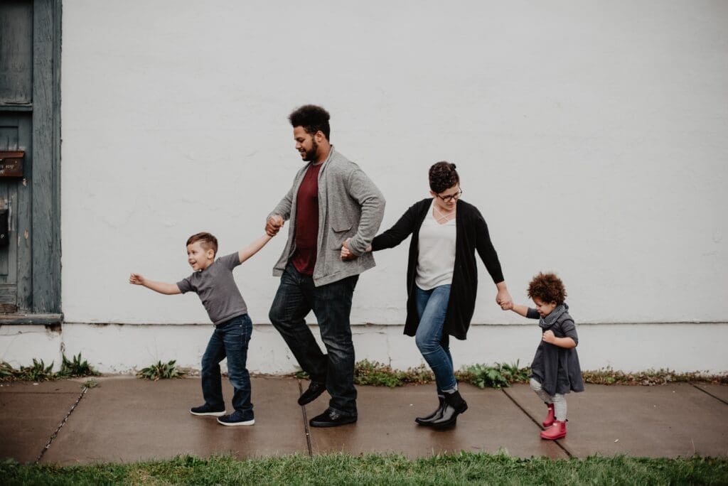 family of 4 walking down street holding hands