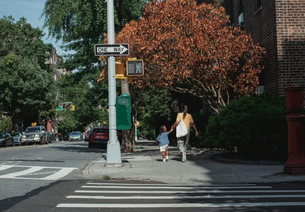 woman and child on a sidewalk, you can see the streetscape, includes a crosswalk and a right of way for pedestrians