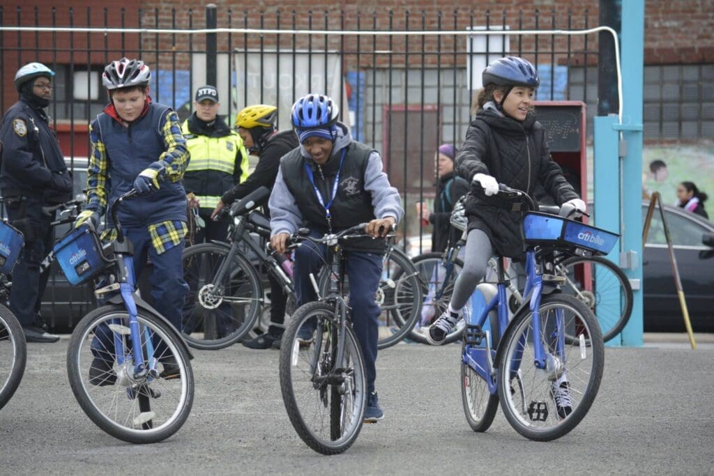 A group of three young people who were a part of the Youth Bike Summit are taking off on their bikes. 