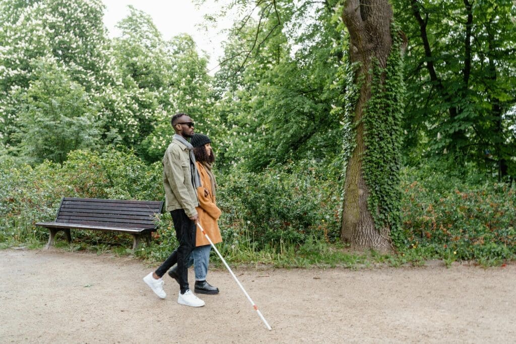 a couple is walking on a trail, they are holding arms, one has a walking stick