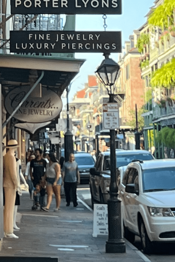 Scene from the French Quarter in New Orleans. People linger on the sidewalk, but parked cars dominate.