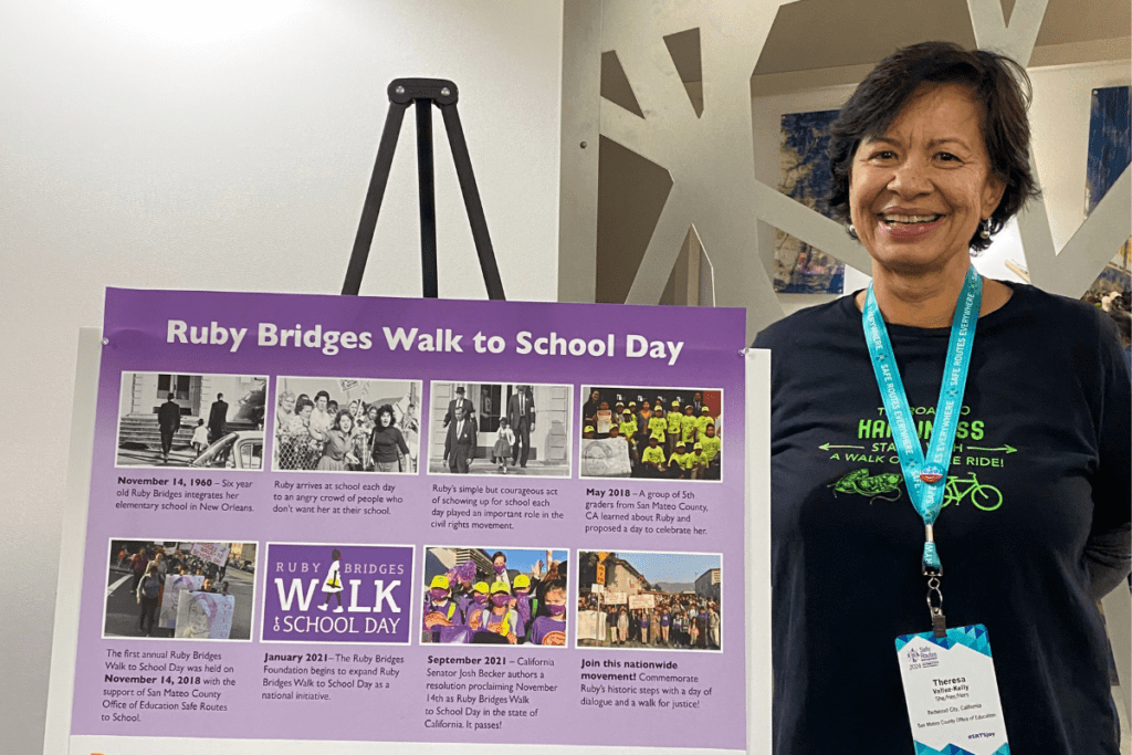 2017 Walking College Graduate Theresa Vallez-Kelly stands beside her her board presenting the Ruby Bridges Walk to School Day on behalf of San Mateo County Office of Education