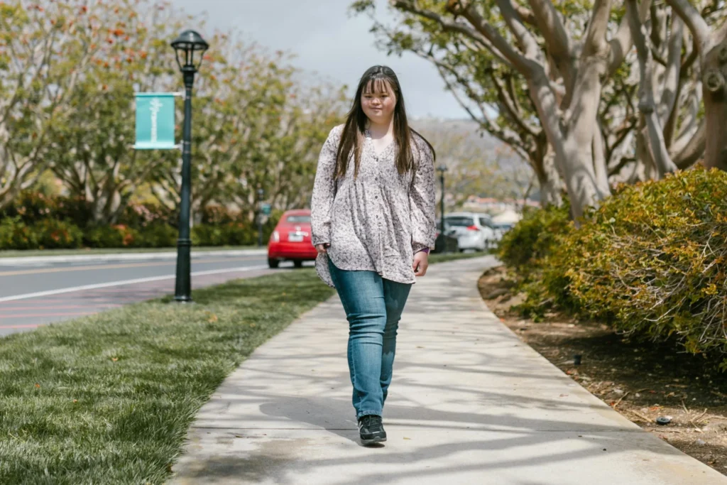 A young woman walks down a green sidewalk.