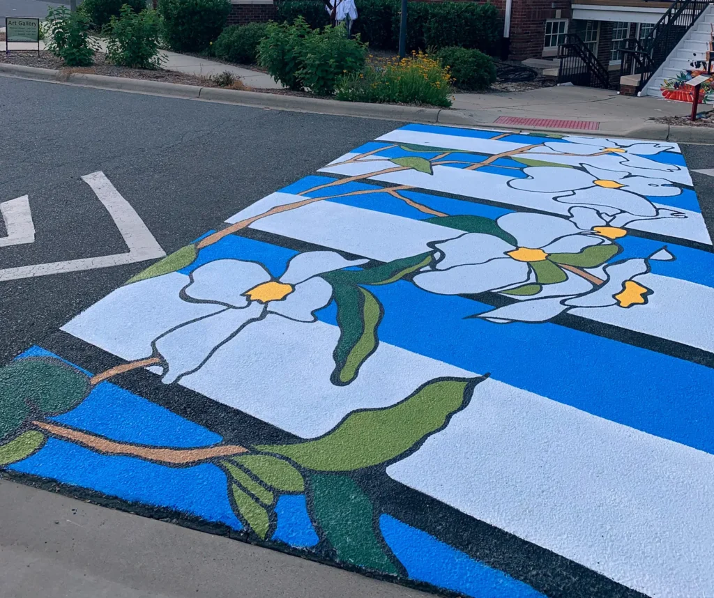 a picture of a colorful and vibrant sidewalk that has white painted flowers with green leaves and blue, white and black stripes