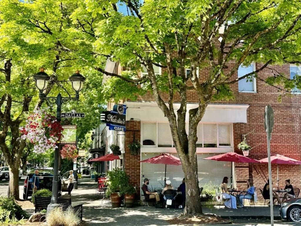 a streetscape with sidewalk seating, a public bench, and wide open walk areas